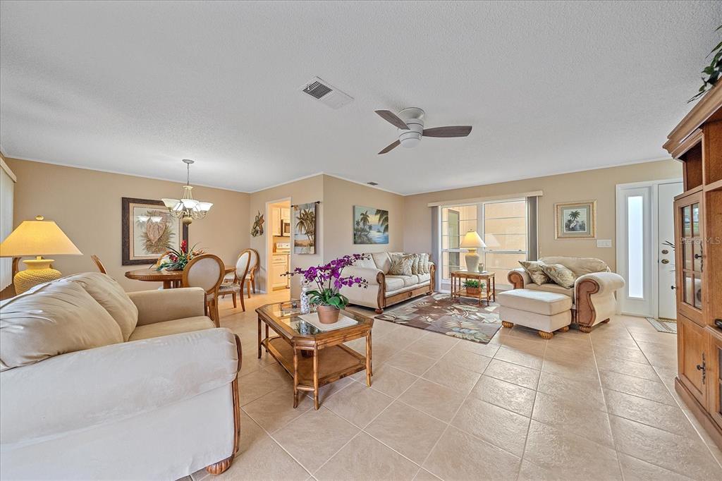 A living room with beige tile floors, neutral walls, a ceiling fan, and tropical-style furniture — 3135 GLEN ELYN BOULEVARD UNIT 13, SARASOTA, FL