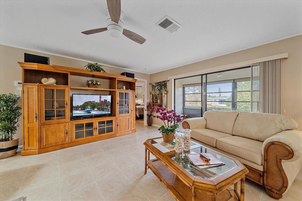 A living room features tile flooring, a large wooden entertainment center, and a beige sofa — 3135 GLEN ELYN BOULEVARD UNIT 13, SARASOTA, FL
