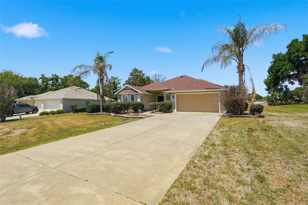 A single-story house with a tan exterior, a two-car garage, and two palm trees — 5013 HARBOR HEIGHTS, LADY LAKE, FL