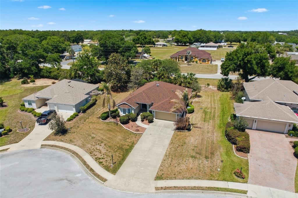 An aerial view shows three suburban houses with driveways and lawns on a sunny day — 5013 HARBOR HEIGHTS, LADY LAKE, FL