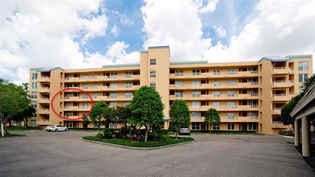 A multi-story tan apartment building features a red circle highlighting a stack of balconies — 4570 PINEBROOK CIRCLE UNIT 302, BRADENTON, FL