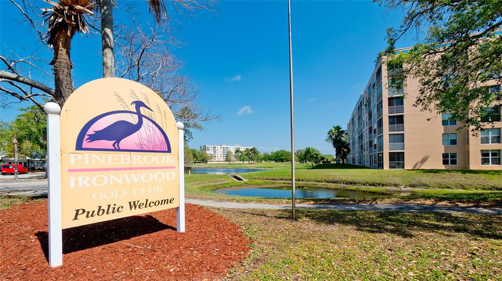 A sign for Pinebrook Ironwood Golf Club stands before a pond and apartment building — 4570 PINEBROOK CIRCLE UNIT 302, BRADENTON, FL