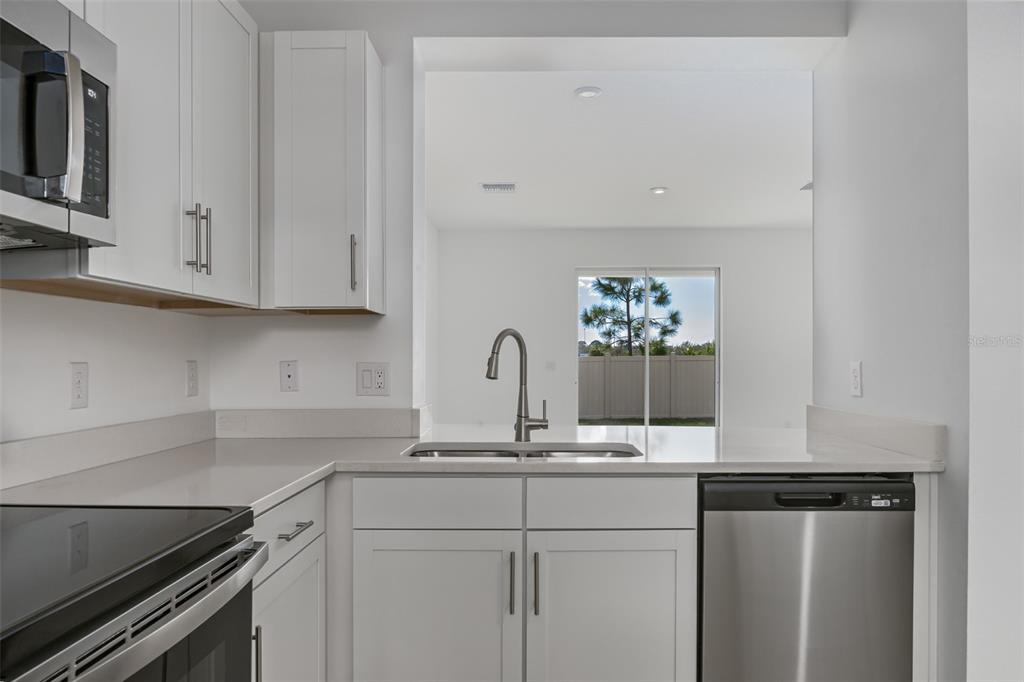A modern kitchen features white cabinets, stainless steel appliances, and a view of the backyard — 6357 FAIRMONT LANE, PALMETTO, FL