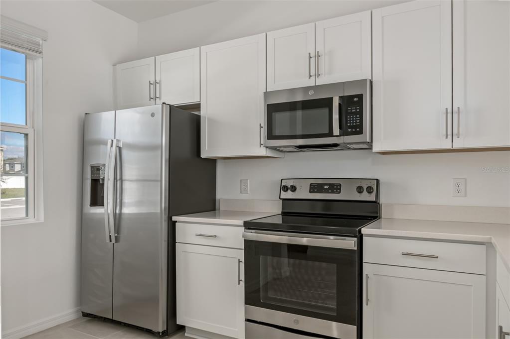 A kitchen features white cabinets, stainless steel appliances, and light countertops — 6357 FAIRMONT LANE, PALMETTO, FL