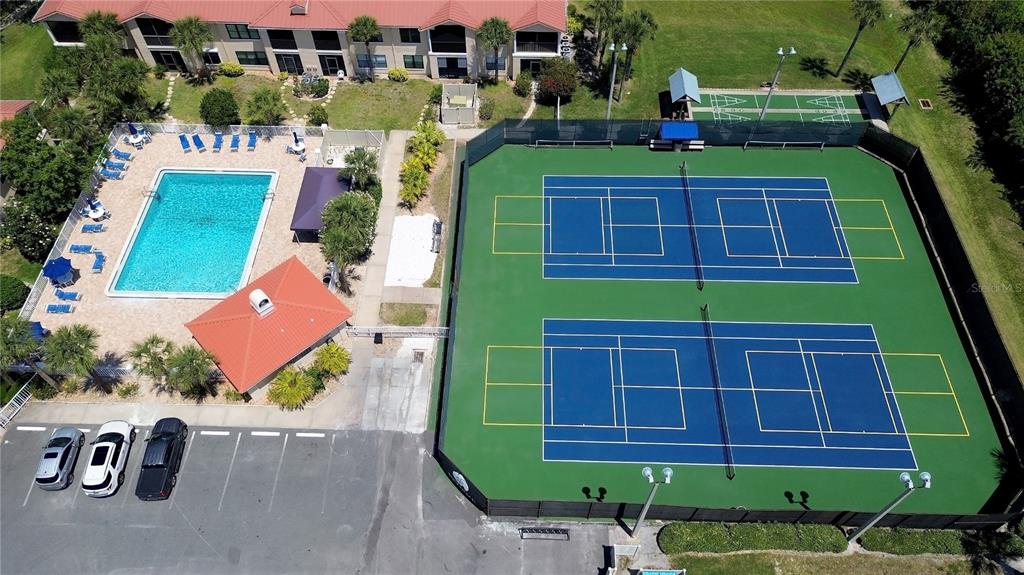 An aerial view shows several multi-story residential buildings with orange tile roofs and landscaping — 441 BOUCHELLE DRIVE UNIT 202, NEW SMYRNA BEACH, FL