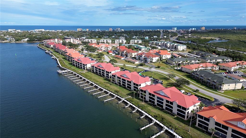An aerial view shows a community swimming pool, a hot tub, and a clubhouse building — 441 BOUCHELLE DRIVE UNIT 202, NEW SMYRNA BEACH, FL