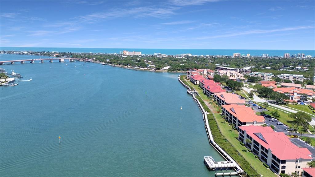 An aerial view shows waterfront condominium buildings with red roofs and private boat docks — 441 BOUCHELLE DRIVE UNIT 202, NEW SMYRNA BEACH, FL