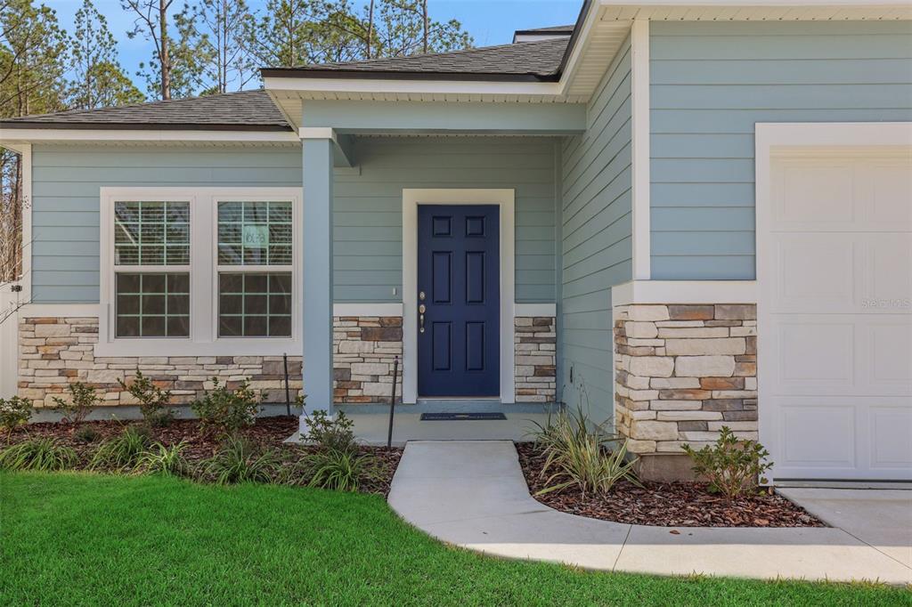 A blue front door is centered on the exterior of a light blue house — 3550 BELSTEAD WAY, ORANGE PARK, FL