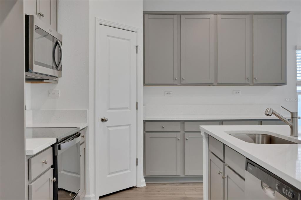 A kitchen features gray cabinets, white countertops, stainless steel appliances, and a center island — 3550 BELSTEAD WAY, ORANGE PARK, FL
