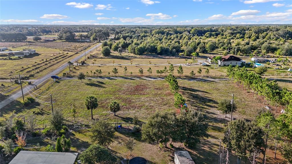 An aerial view shows a large, grassy lot with scattered trees and a nearby road — 18121 BETHLEHEM ROAD, LITHIA, FL