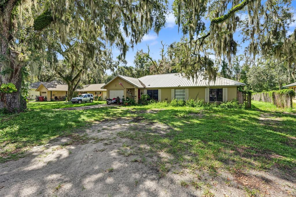 A single-story house with a metal roof and a large, unpaved front yard under trees — 509 E DREW STREET, PLANT CITY, FL