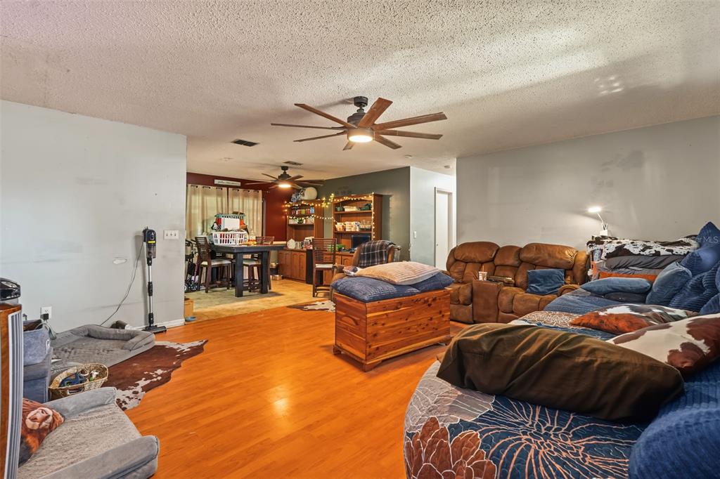 A living room with wood-look flooring, a ceiling fan, and a large brown sectional sofa — 509 E DREW STREET, PLANT CITY, FL
