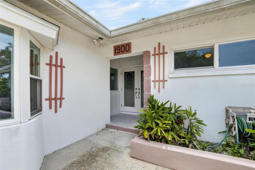 The exterior entrance features a white stucco wall, double glass doors, and a planter box — 1900 STANTON AVE, LARGO, FL