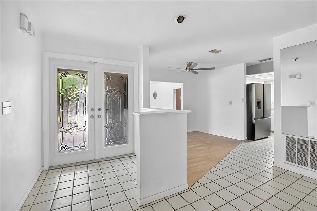 An entryway with white tile floors leads to a living area with wood-look flooring — 1900 STANTON AVE, LARGO, FL
