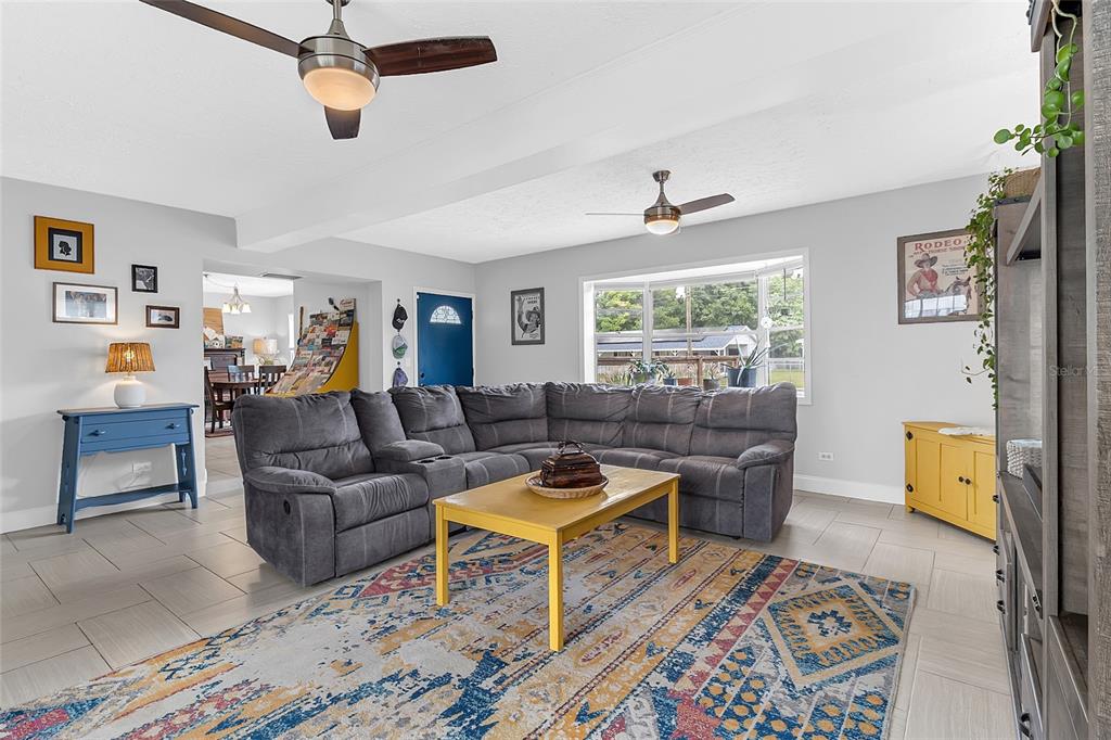 A living room features a gray sectional sofa, a yellow coffee table, and tile flooring — 855 PEARL DRIVE, MOUNT DORA, FL
