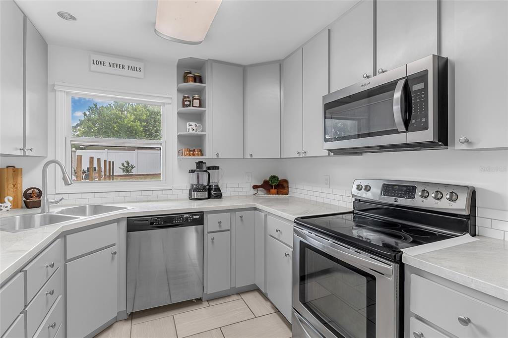 A kitchen with gray cabinets, stainless steel appliances, white countertops, and a subway tile backsplash — 855 PEARL DRIVE, MOUNT DORA, FL