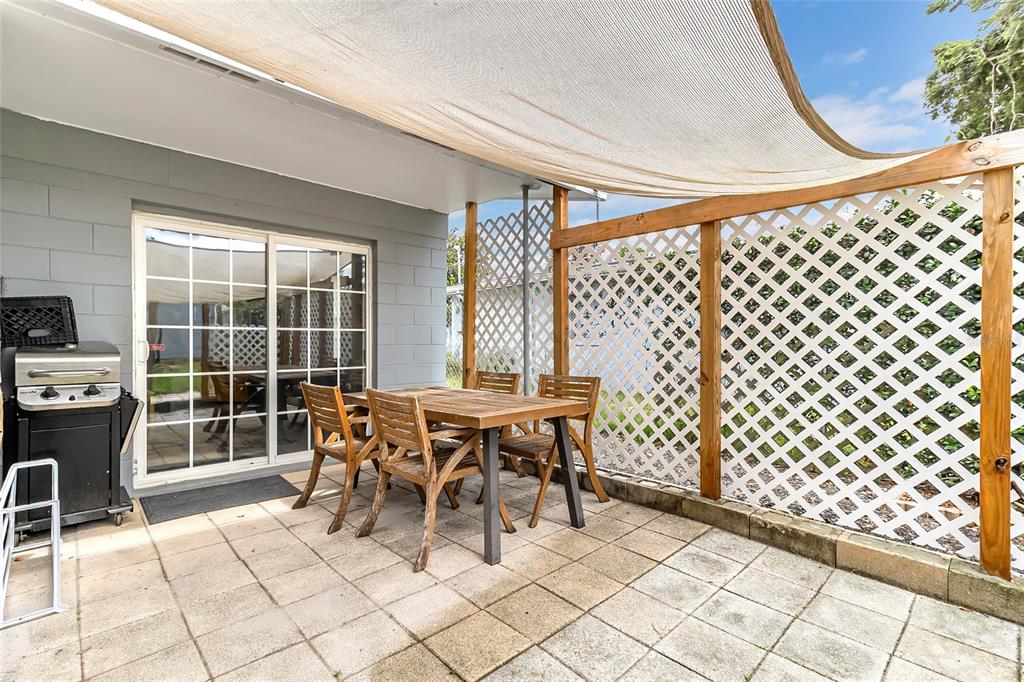 A patio features a dining set, a grill, and a lattice privacy screen under a canopy — 855 PEARL DRIVE, MOUNT DORA, FL
