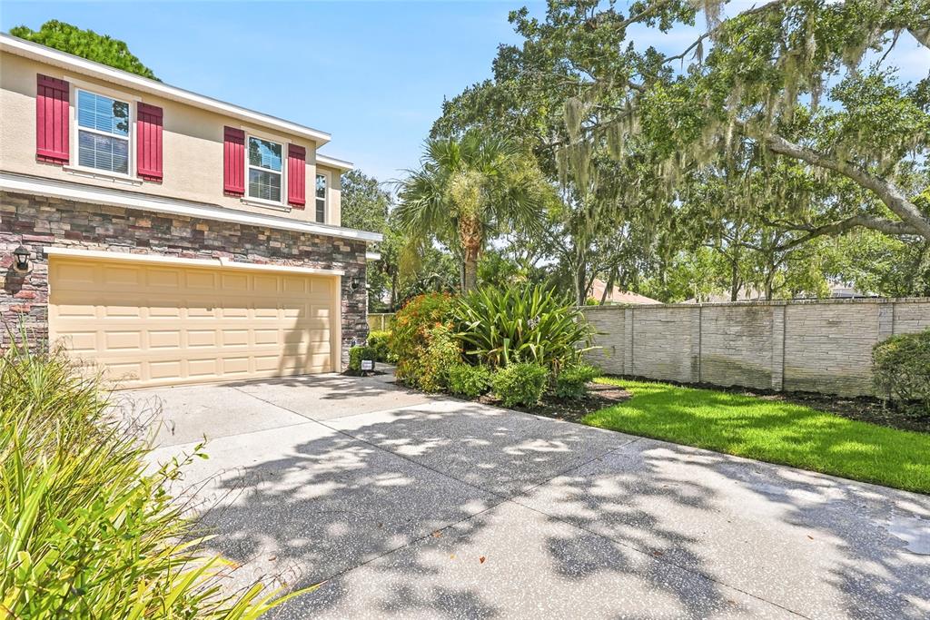 A two-story house with a stone facade, beige garage door, and red shutters — 13105 CANOPY CREEK DRIVE, TAMPA, FL