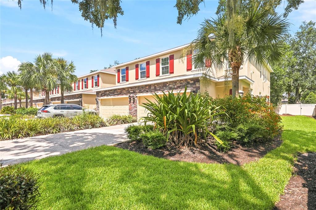 A two-story townhouse with a stone facade, red shutters, and a palm tree in front — 13105 CANOPY CREEK DRIVE, TAMPA, FL
