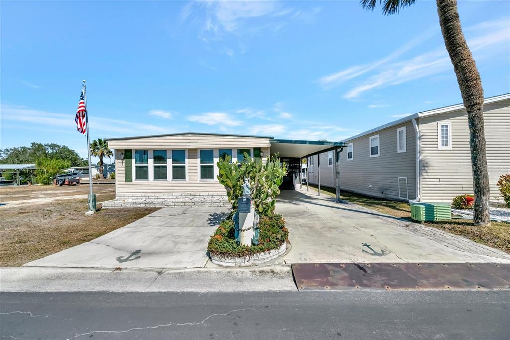 A single-story manufactured home features a concrete driveway, a carport, and a flag pole — 132 W SAINT LUCIA LOOP, APOLLO BEACH, FL
