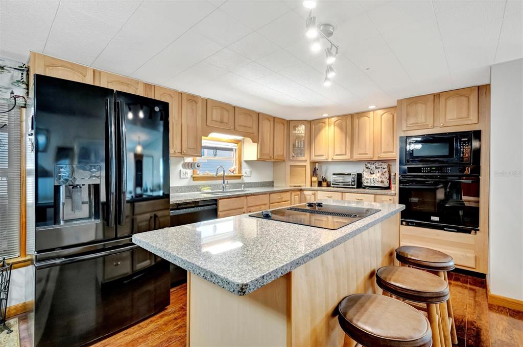A kitchen with light wood cabinets, granite countertops, a center island, and black appliances — 132 W SAINT LUCIA LOOP, APOLLO BEACH, FL