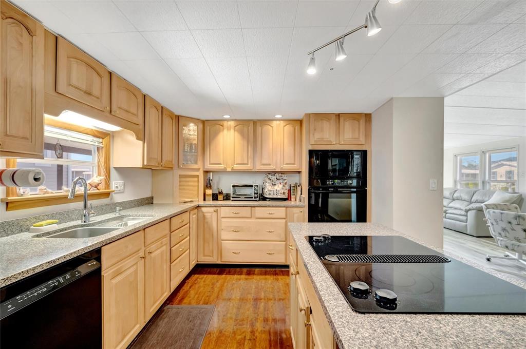 A kitchen features light wood cabinets, granite countertops, a black dishwasher, and a center island — 132 W SAINT LUCIA LOOP, APOLLO BEACH, FL