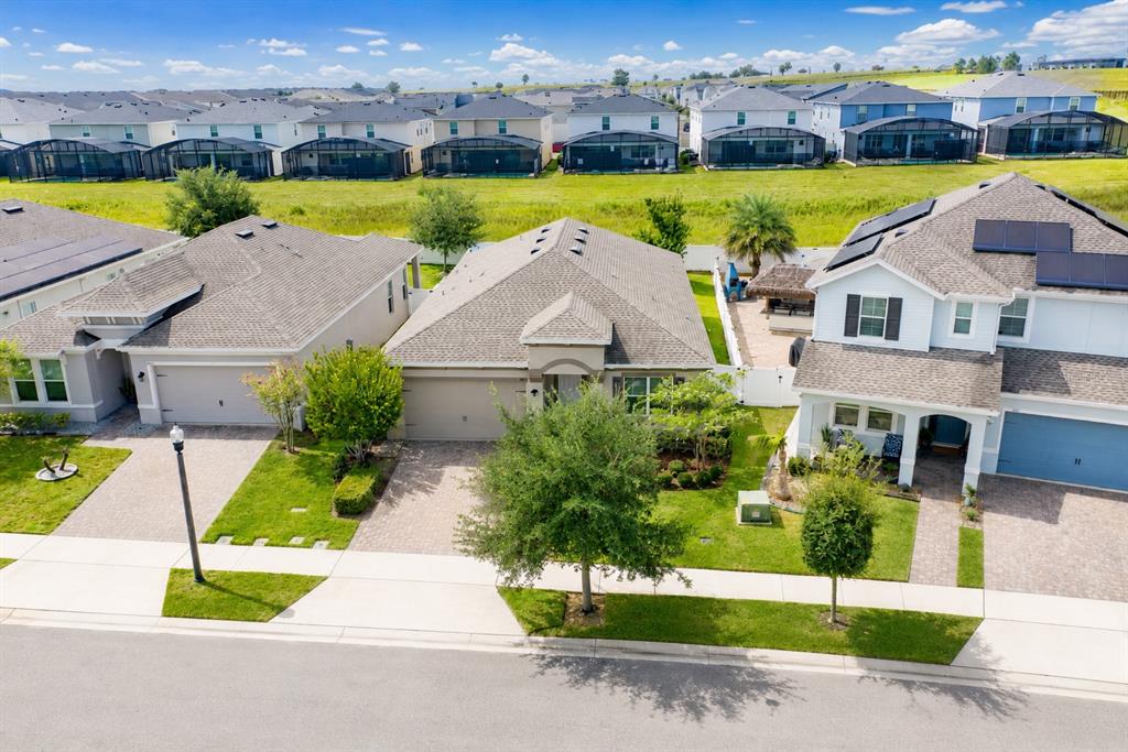 An aerial view shows three suburban houses with paved driveways and green lawns — 9184 OLMO COURT, DAVENPORT, FL