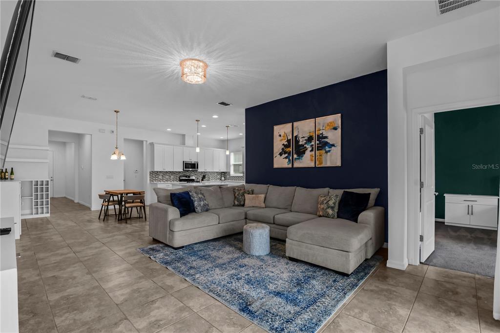 A living room with a grey sectional sofa, blue area rug, and dark blue accent wall — 9184 OLMO COURT, DAVENPORT, FL