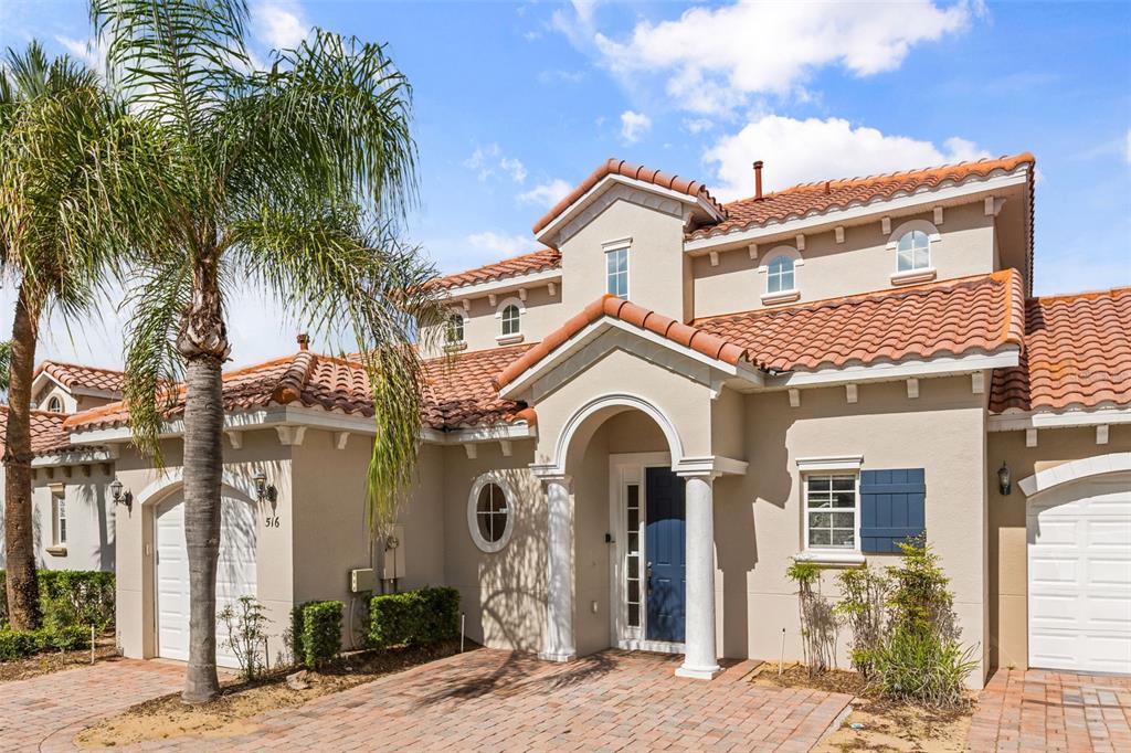 A beige house with a tiled roof, blue front door, and a palm tree in front — 516 BRUNELLO DRIVE, DAVENPORT, FL
