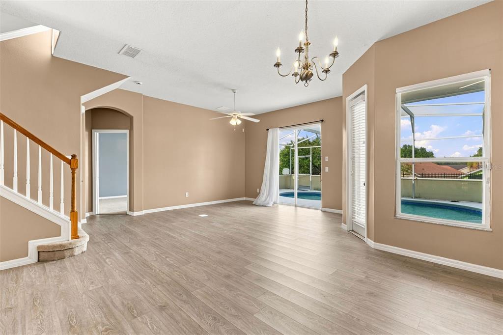 A living room with light wood flooring, a staircase, a chandelier, and a pool view — 516 BRUNELLO DRIVE, DAVENPORT, FL