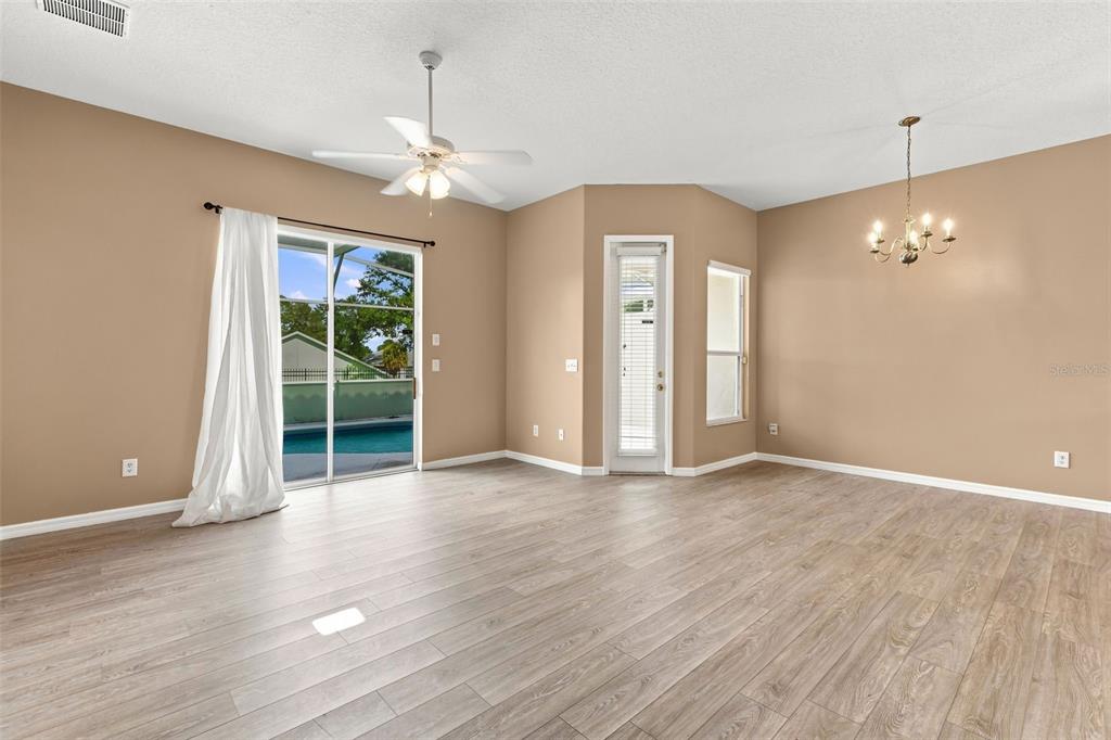 An empty living area with wood-look flooring, a ceiling fan, and a sliding glass door — 516 BRUNELLO DRIVE, DAVENPORT, FL
