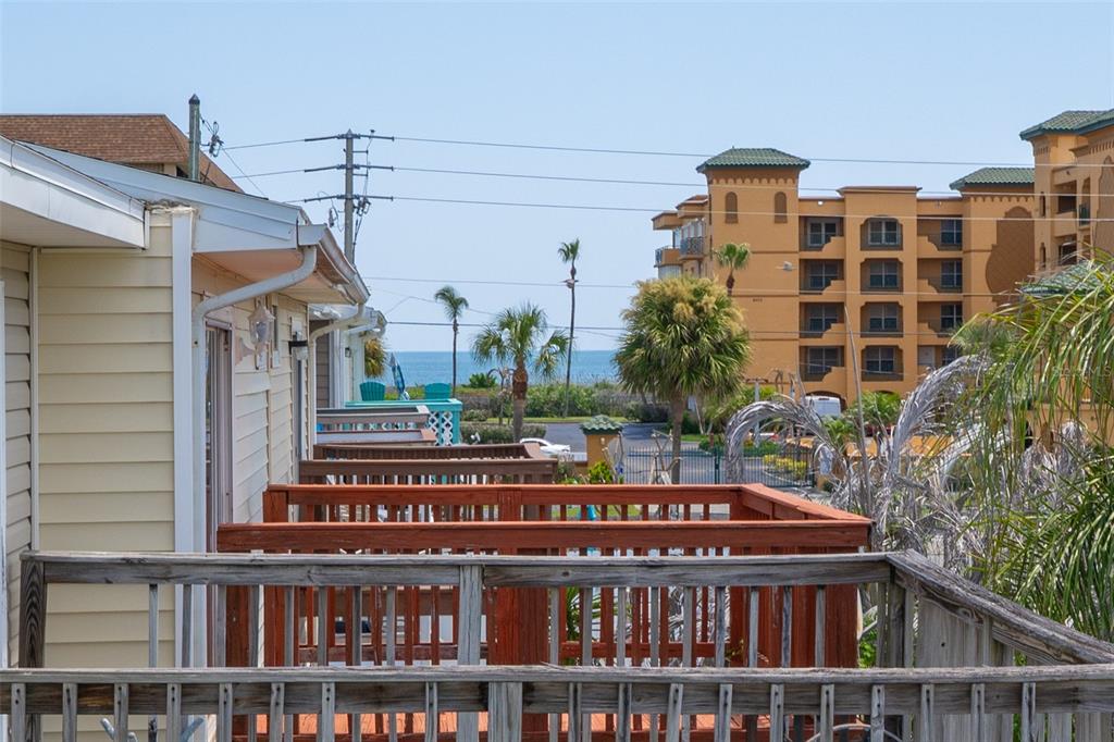 An elevated wooden deck overlooks a parking area, palm trees, and the ocean in the distance — 241 CHERIE DOWN LANE, CAPE CANAVERAL, FL