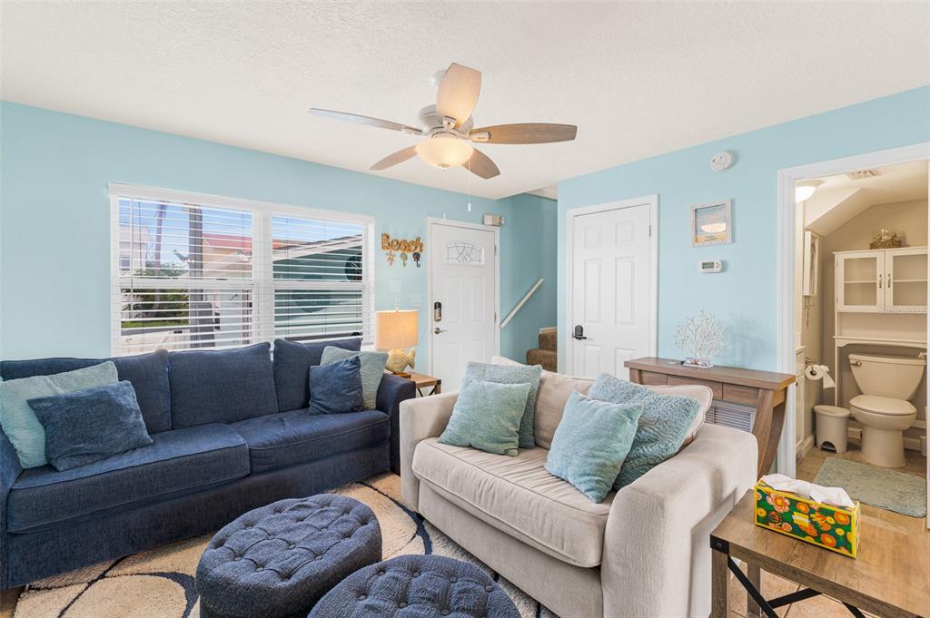 A living room features a blue sofa, a beige loveseat, and an adjacent bathroom — 241 CHERIE DOWN LANE, CAPE CANAVERAL, FL