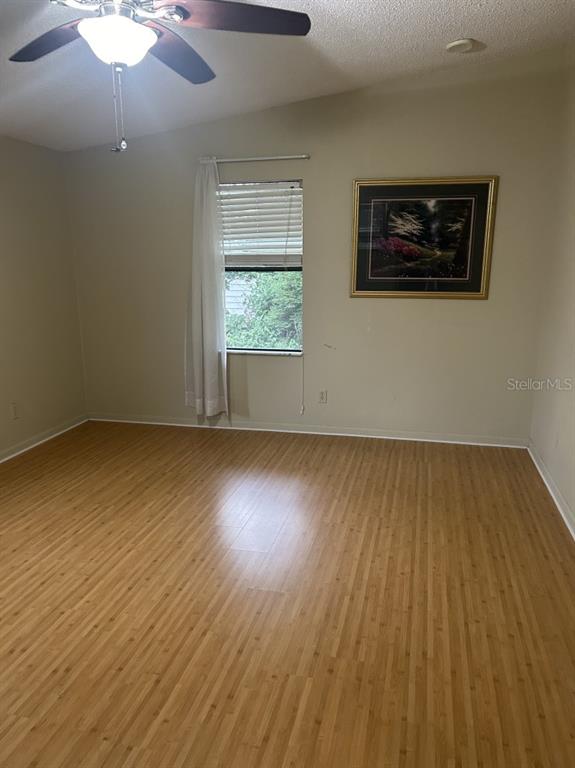 A living room with wood-look flooring features a central wall with a kitchen pass-through window — 1550 HILLCREST DRIVE, THE VILLAGES, FL