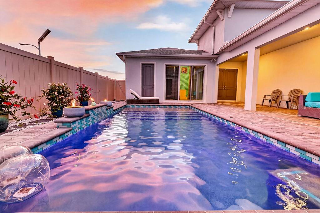 A rectangular swimming pool sits in a backyard patio area next to a house — 10470 PURPLE THISTLE WAY, SAN ANTONIO, FL