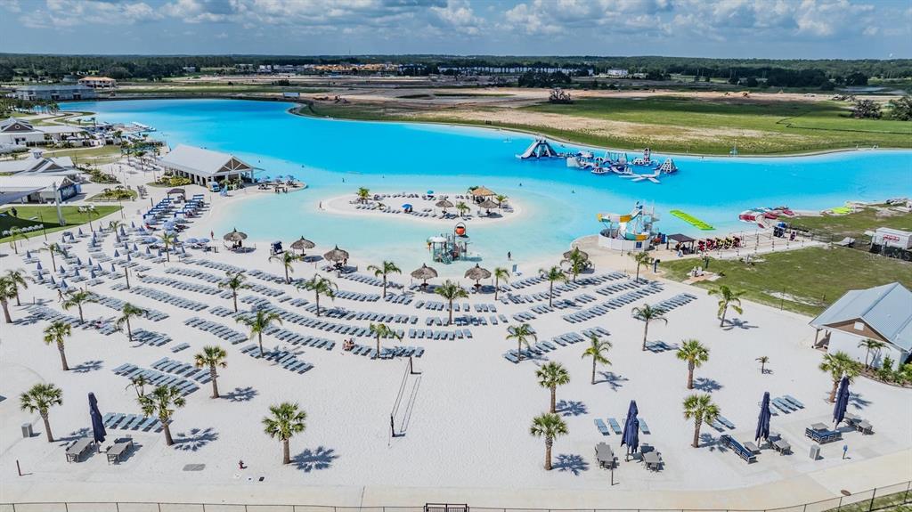 An aerial view shows a large turquoise lagoon with a sandy beach and lounge chairs — 10470 PURPLE THISTLE WAY, SAN ANTONIO, FL