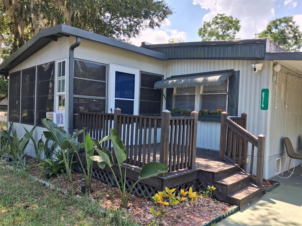 A single-story mobile home features a wooden deck, screened-in porch, and a metal awning — 8714 ALLAMANDA STREET, HUDSON, FL