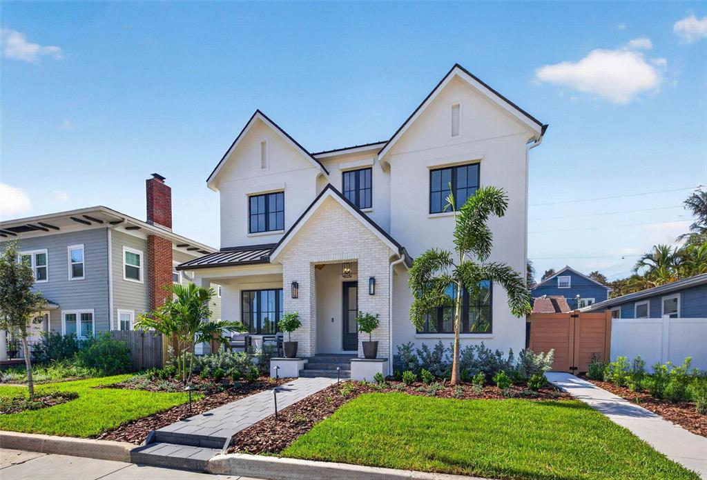 A two-story white house with a brick entryway, dark window frames, and a landscaped front yard — 142 22ND AVENUE N, ST PETERSBURG, FL