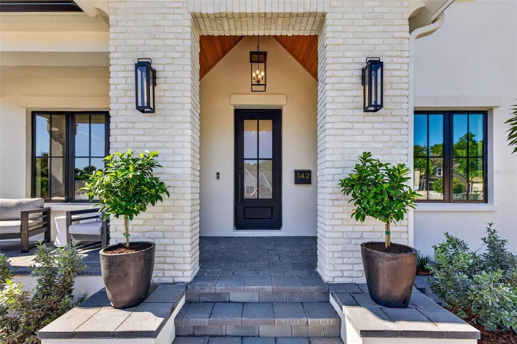 A front entryway features a black door, white brick columns, and two potted topiary trees — 142 22ND AVENUE N, ST PETERSBURG, FL