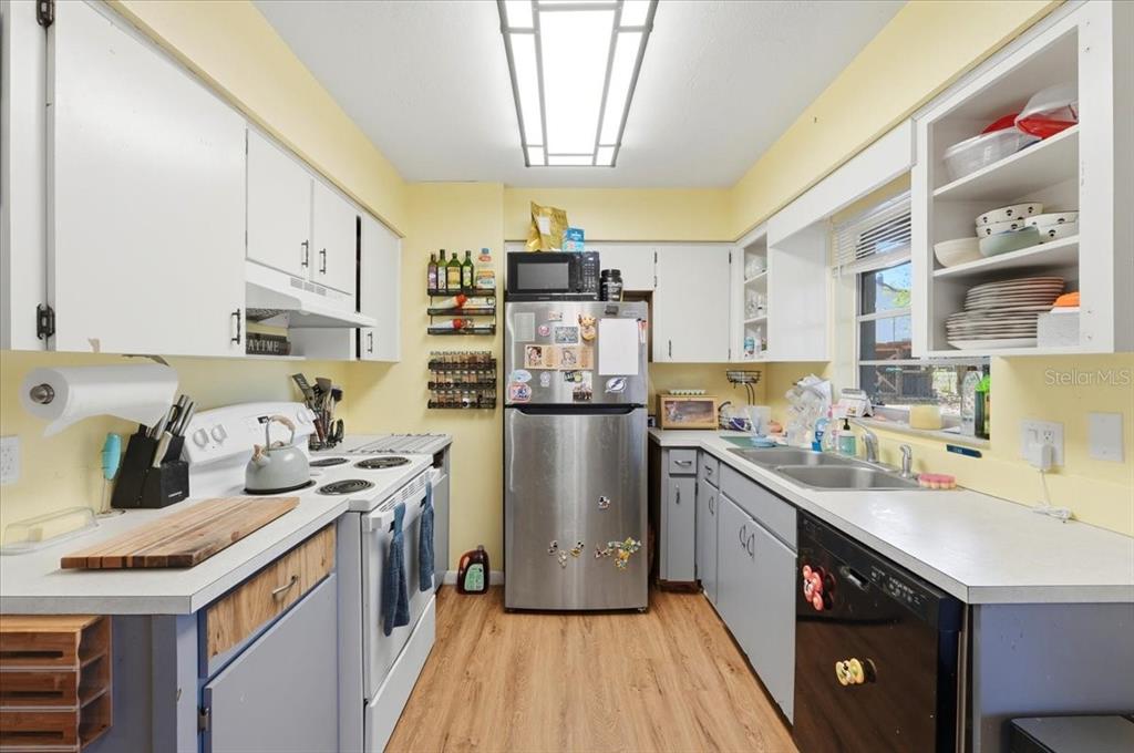 A kitchen with white cabinets, stainless steel appliances, yellow walls, and light wood-look flooring — 215 CARLA ANN COURT, AUBURNDALE, FL