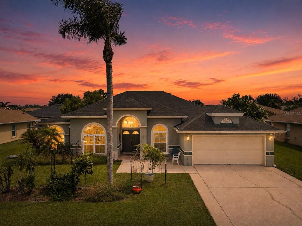 A single-story house with a two-car garage and a palm tree at sunset — 2856 MIDDLETON CIRCLE, KISSIMMEE, FL