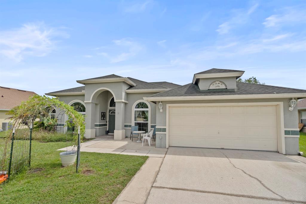 A single-story house with a light gray stucco exterior, a two-car garage, and a front patio — 2856 MIDDLETON CIRCLE, KISSIMMEE, FL