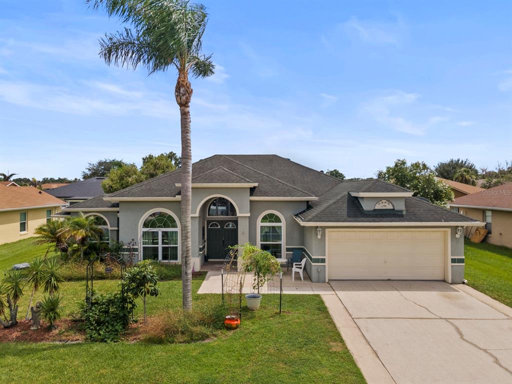 A single-story house with a gray stucco exterior, a two-car garage, and a palm tree — 2856 MIDDLETON CIRCLE, KISSIMMEE, FL