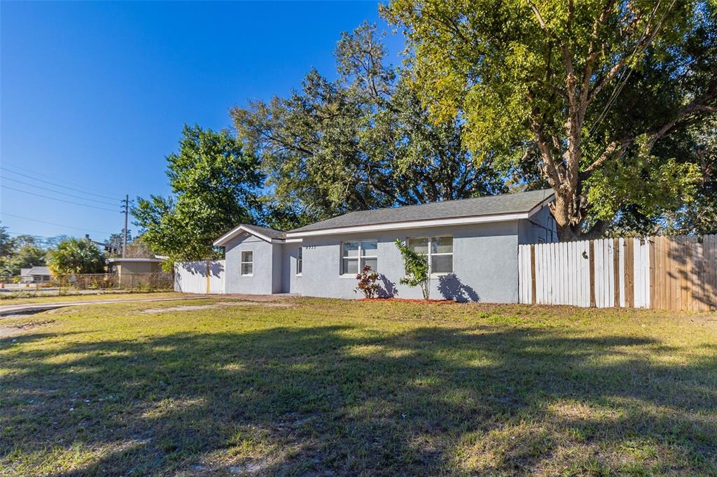 A single-story gray house with a white fence sits on a grassy lot under trees — 4933 BALBOA DRIVE, ORLANDO, FL
