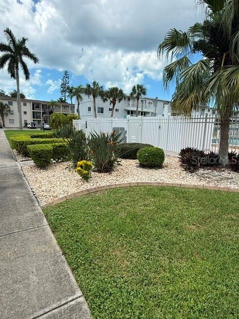 A sidewalk leads past a landscaped garden bed toward a multi-story apartment building — 2223 SUNSET DRIVE UNIT E24, BRADENTON, FL