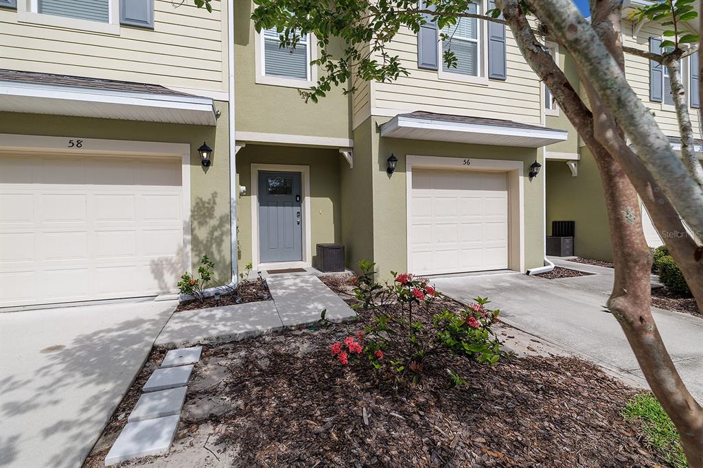 The exterior of two adjacent townhomes features beige siding, gray garage doors, and a front entrance — 58 BELLA OAKS DRIVE, PORT ORANGE, FL