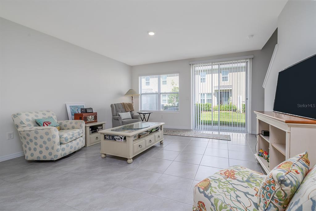 A living room features light tile floors, a coffee table, armchairs, and sliding glass doors — 58 BELLA OAKS DRIVE, PORT ORANGE, FL