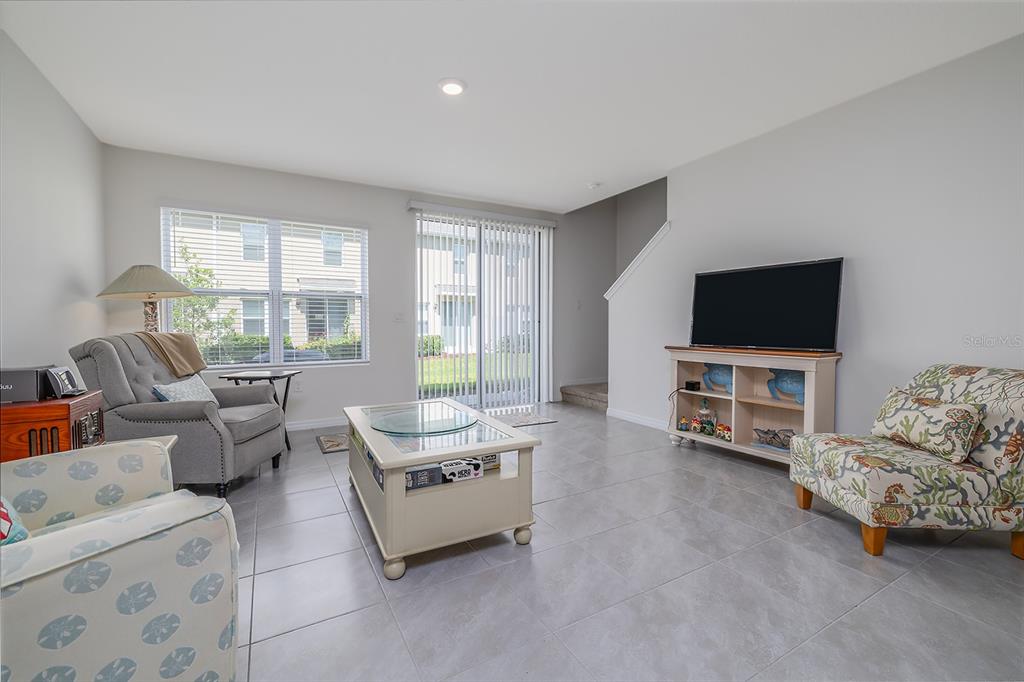 A living room features light tile flooring, a coffee table, a television console, and seating — 58 BELLA OAKS DRIVE, PORT ORANGE, FL