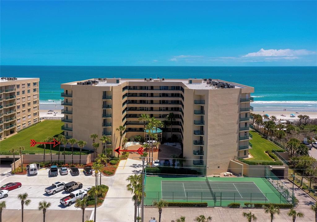 An aerial view shows a multi-story beachfront condominium building with a tennis court and parking — 4575 S ATLANTIC AVENUE UNIT 6101, PORT ORANGE, FL