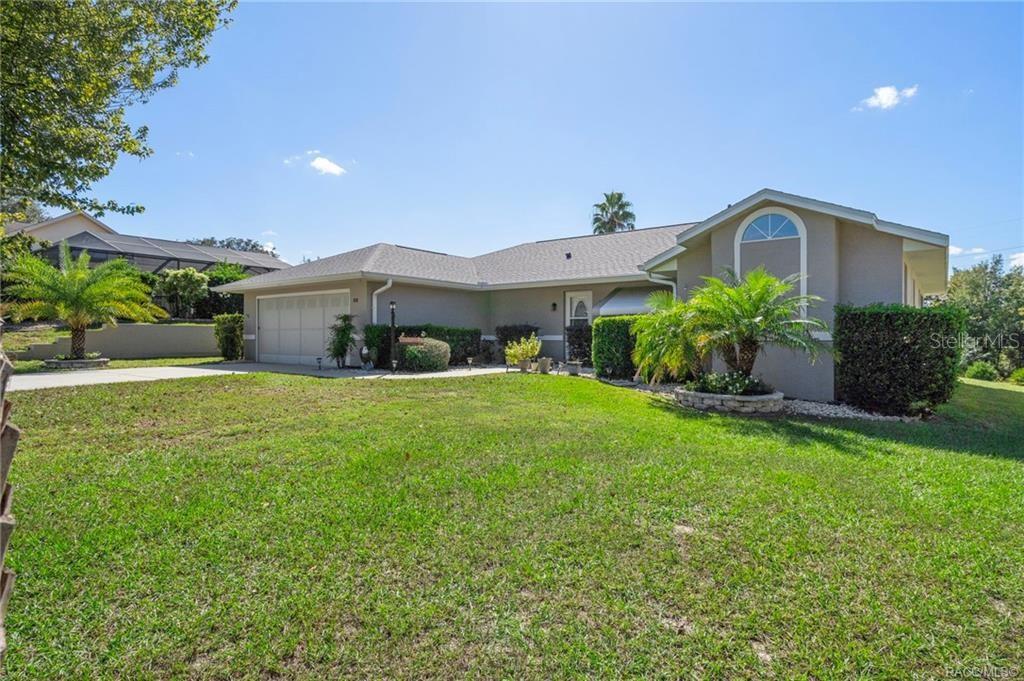 A single-story house with a two-car garage, beige stucco exterior, and a landscaped front yard — 1342 S BROOKFIELD DRIVE, LECANTO, FL